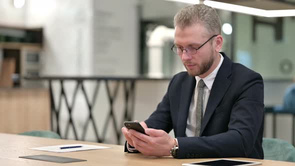 Attractive Businessman Using Smartphone in Office