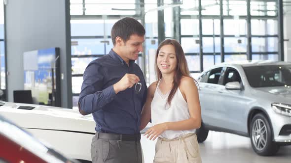 Happy Loving Couple Embracing Near Their New Luxury Car at Dealership