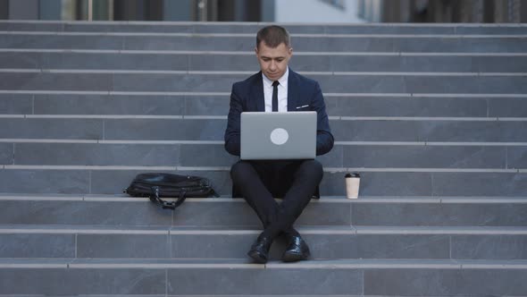 Fired Entrepreneur in Suit Using Laptop for Online Job Searching Sitting at Business Area
