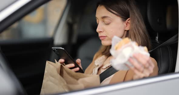 Woman Typing on a Smart Phone While Having a Snack in a Vehicle