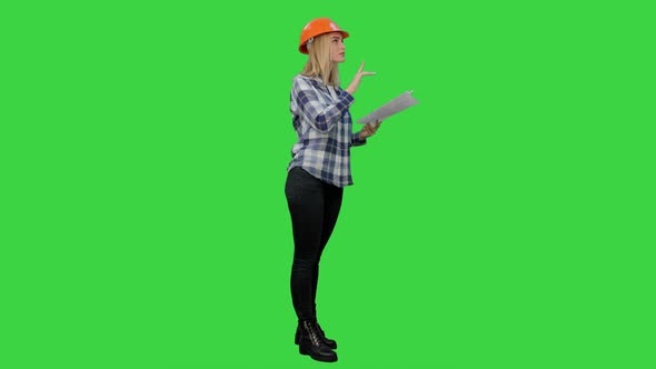 Young Engineer Woman Reading Technical Drawings and Analyze It on a Green Screen, Chroma Key.