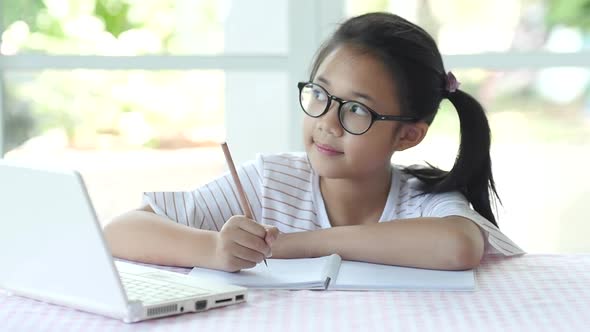 Beautiful Asian Girl Wear Glasses Writing To Notebook On The Table