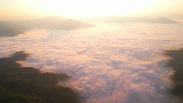 4K Flying through the clouds above mountain tops. Tropical forest with smoke and fog.