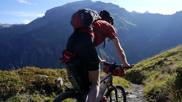 A man mountain biking across a European mountain range.