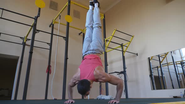 Muscular Gymnast Doing Push Ups in Handstand at Gym