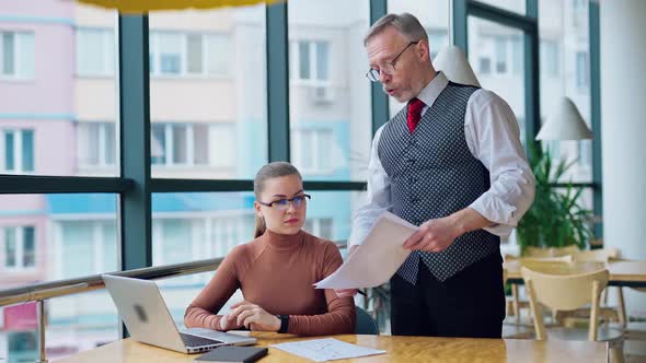 Strict elderly businessman talks to a secretary. 