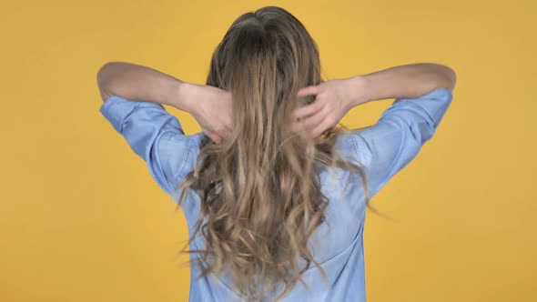 Young Girl Playing with Hairs Turning Around And Smiling Isolated on Yellow Background