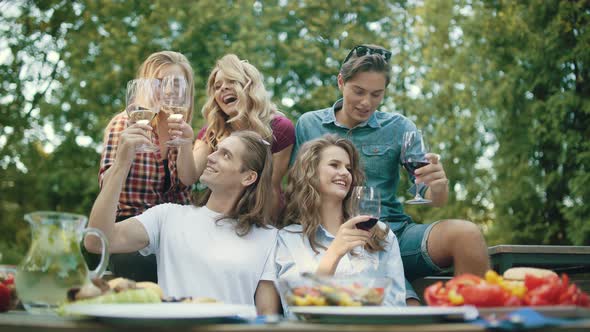 Friends Toasting With Drinks At Dinner Party Outdoors