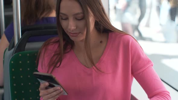 Young and Happy Woman Using Smartphone While Sitting Near the Window in the Public Transport