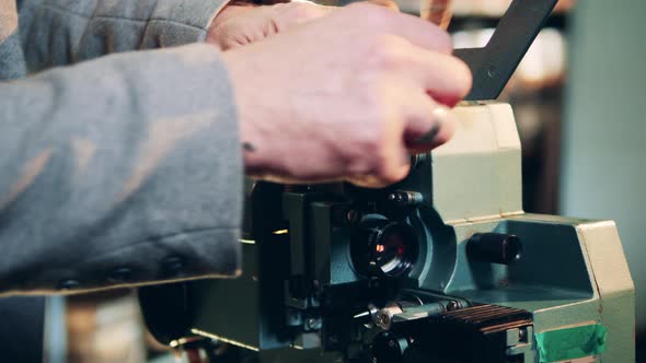 Old Film Tape is Getting Put Into the Projector By a Specialist