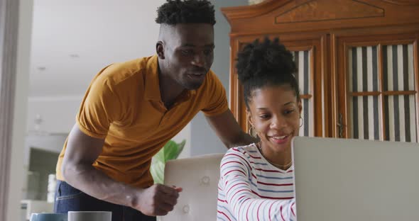 Video of happy african american couple using laptop, paying bills