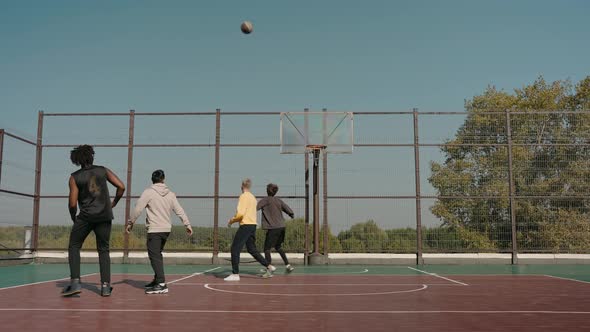 Man Scores Ball Into the Basket Team Cheers on a Basketball Court in Park
