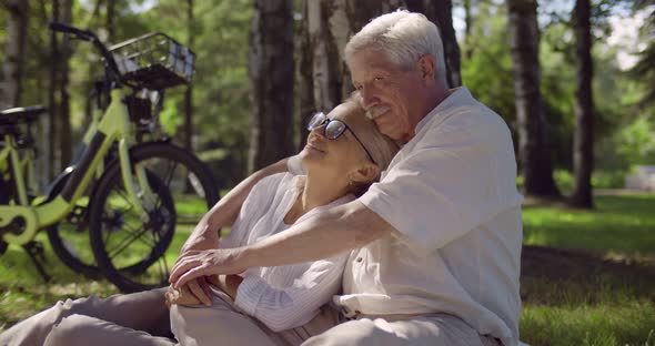 Portrait of Senior Caucasian Couple Sitting in Park Together and Hugging