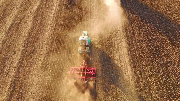 Aerial View Modern Red Tractor on the Agricultural Field on Sunset Time. Tractor Plowing Land and