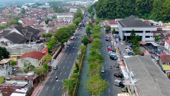 Aerial forward over canal flowing between main roads of Magelang city, Indonesia