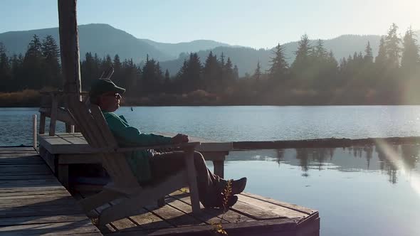 man sitting on dock at sunset