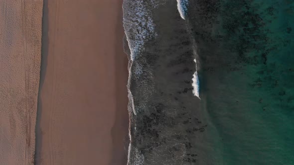 Drone aerial view of an exotic beach with gold sand and turquoise waters in Matadouro, Portugal