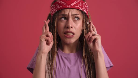 Concentrated hippie woman hoping with crossed fingers at the camera