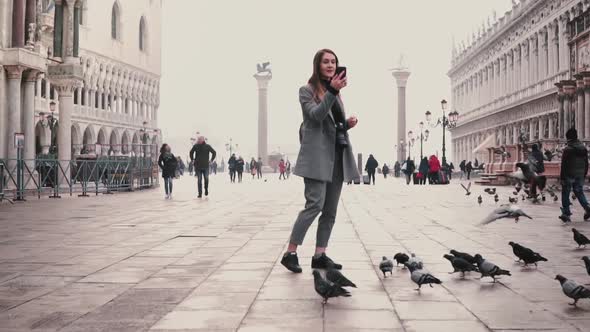 Happy Smiling Tourist Girl Takes Smartphone Photos of Pigeons Flock