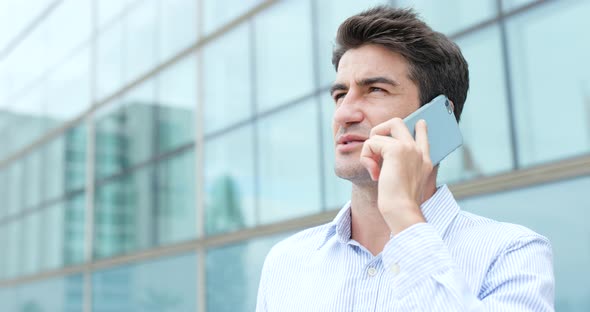 Hispanic man talk to cellphone outside office