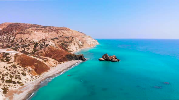 Aerial view of Aphrodite's Rock as camera pulls away along the beach and coastline with beautiful vi