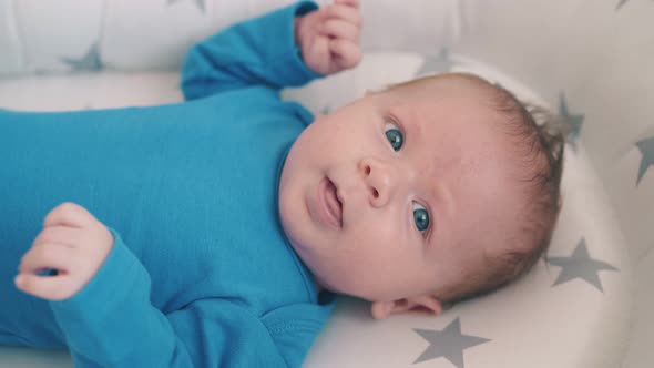 Little Baby Kicks Legs Resting in Soft Cocoon in Child Room