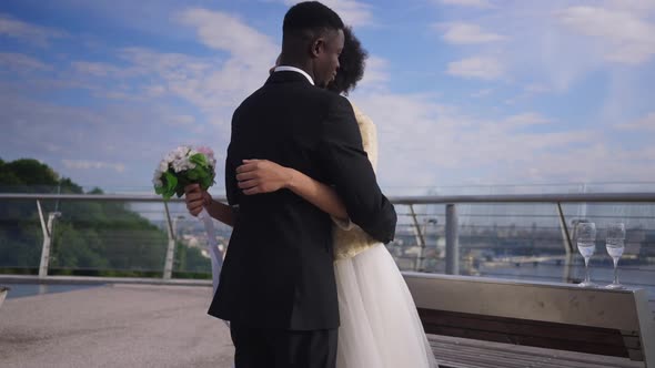 Groom Hugging Bride Standing on Bridge As Live Camera Zoom in to Wedding Bouquet