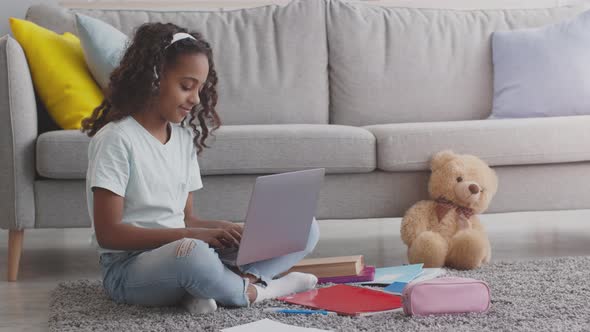 Portrait of Happy African American Girl Typing on Laptop Listening to Music in Headphones Sitting on