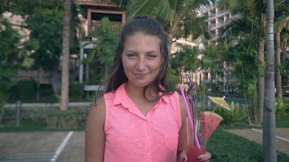 Lady in Beautiful Pink Dress Stands Against Green Palms