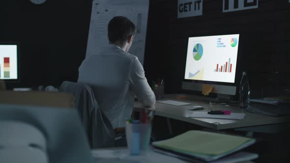 Overworked Business Man Analyzing Financial Chart and Diagram in Night Office