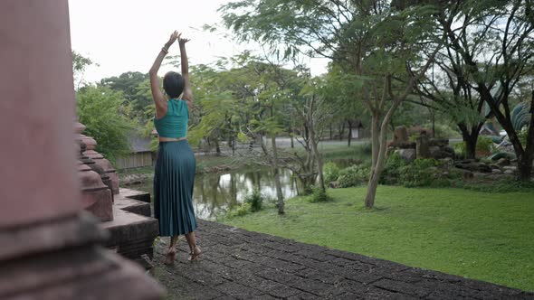 Back View Of A Happy Woman Tourist Wearing Halter Top And Flared Skirt Doing A Ballet Dance Outside