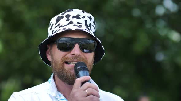 Portrait of a Stylish Bearded Man Speaking Through a Microphone Outdoors