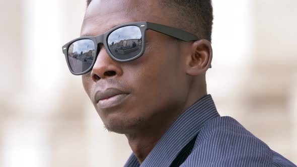 Confident attractive black american man taking off sunglasses, staring at camera