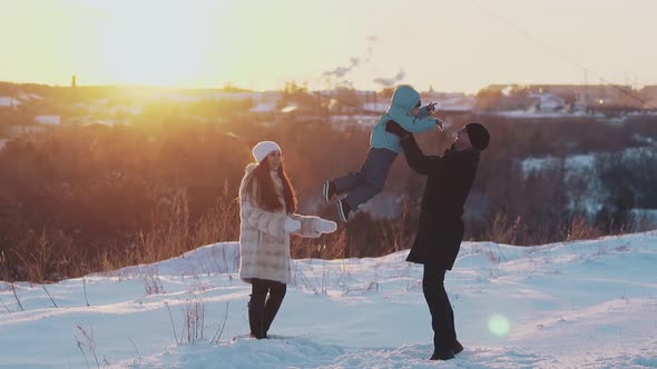 Family Entertains on White Snow Ground Against Blurry Roofs