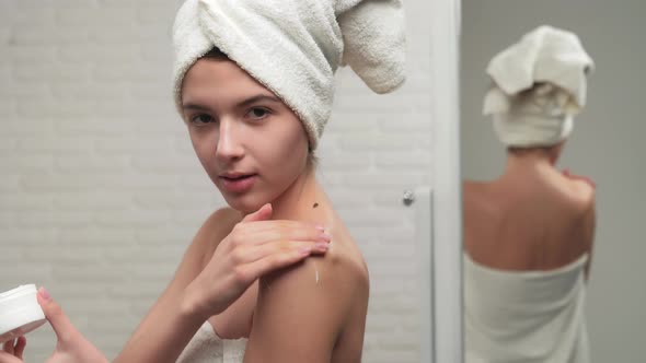 Woman in Towel Putting Cream on Shoulder