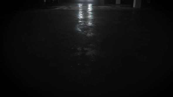 Dark Underground Parking Lot Concrete Floor Car Headlights Backlight Dolly in Gliding Low Angle Shot