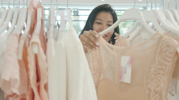 Slow Motion of Pretty Asian Woman Speaking on Cell Phone and Looking at Clothing in Shop