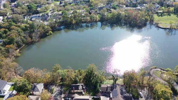 An aerial drone view of Grant Pond in a Long Island, NY suburb. The camera truck right, tilted down