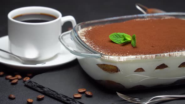 Tiramisu Dessert in Glass Baking Dish and Cup of Fresh Hot Espresso Coffee on Concrete Background