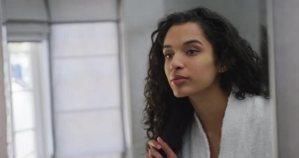 Mixed race woman brushing her hair in bathroom