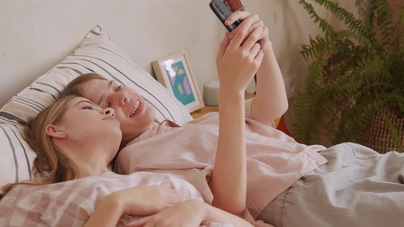 Twin Sisters Relaxing and Using Mobile Phone