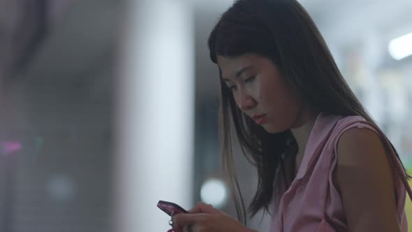 A Lady Sitting in Airport and Checking the News Feed on Her Phone