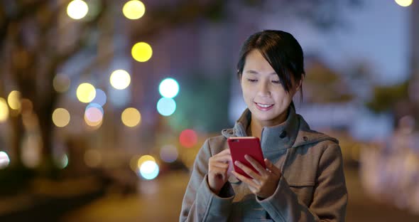 Woman check on smart phone in city at night