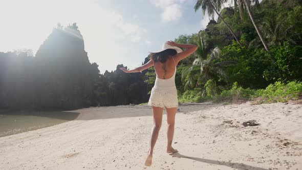 Woman Running Along And Turning To Smile At Camera On Beach