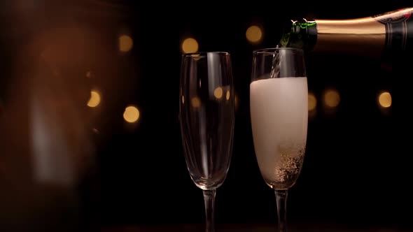 Close-up of the Bartender Pouring Champagne Into a Glasses on a Black Background, the Glass Has a