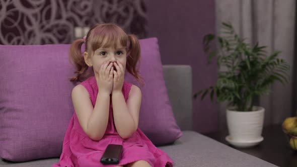 Little Child Sitting While Watching TV. Scared Kid Girl Watch Horror Movie