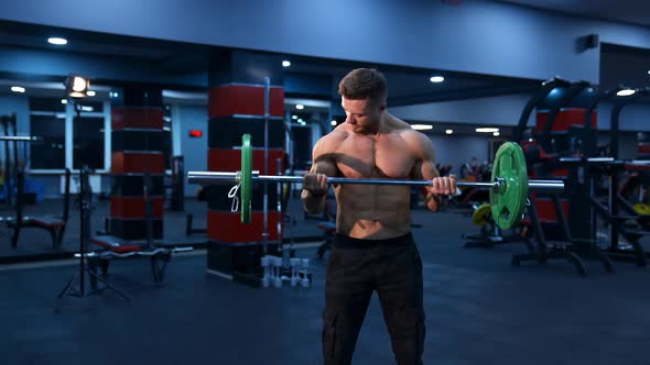 Athletic man in gym exercising with barbell. Bodybuilder with perfect body.