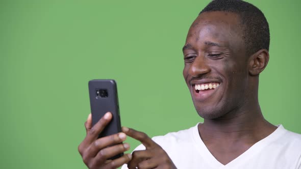 Young African Man Using Phone Against Green Background