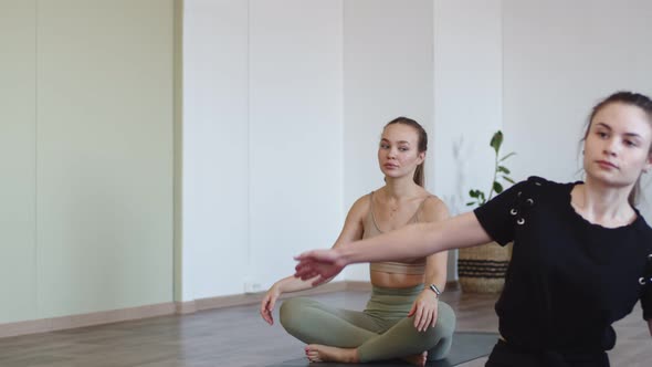 Woman Performs Stretching Under Guidance of Yoga Instructor at Fitness Club Front View