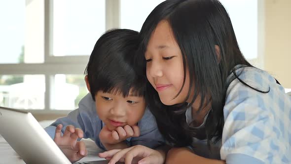 Cute Asian Children  Lying In Bed And Using Laptop On White Bed